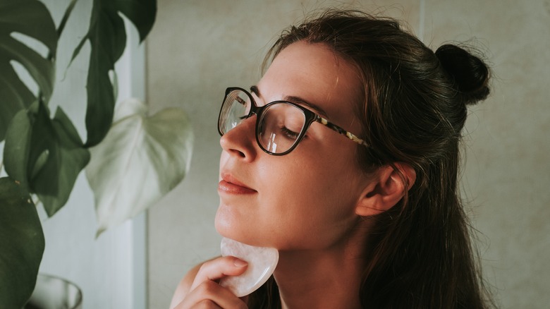 Woman performing gua sha on jawline