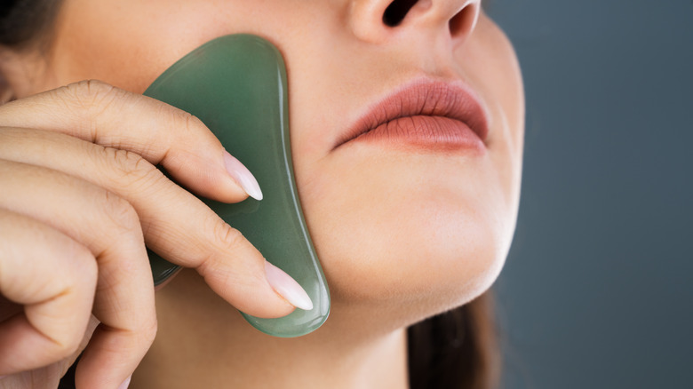 Close up of woman using gua sha