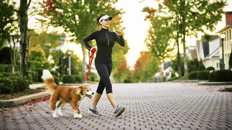 Woman walking dog while working out