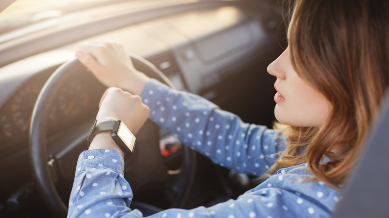 woman looking watch while driving