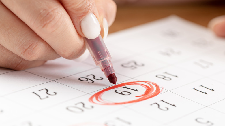 woman circling number in calendar 