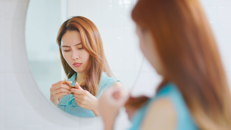 woman looking at her hair in the mirror