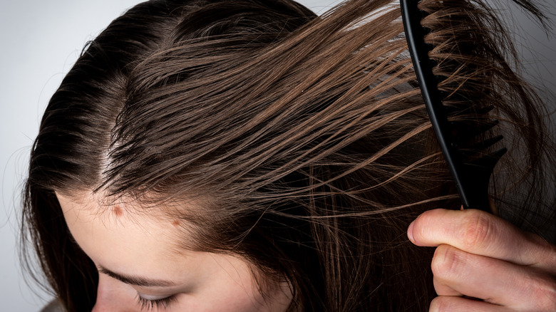 Woman combing greasy hair 