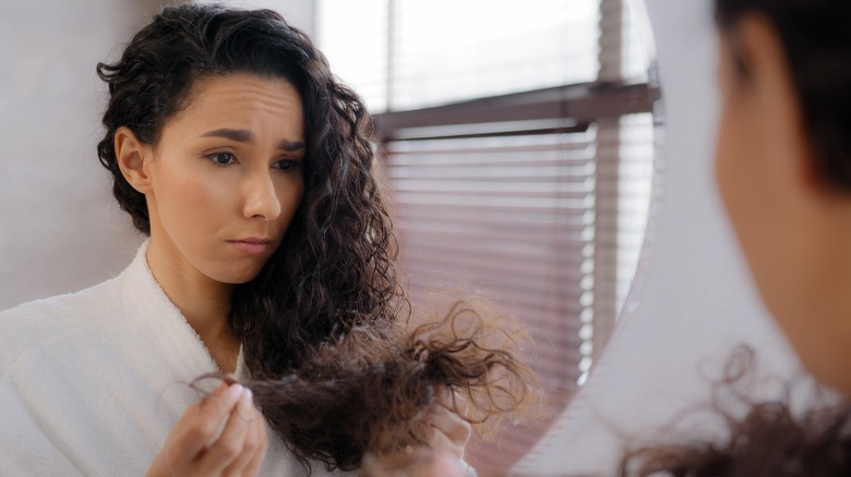 Woman looking at hair in mirror