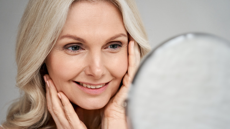 Woman hand on face looking in mirror