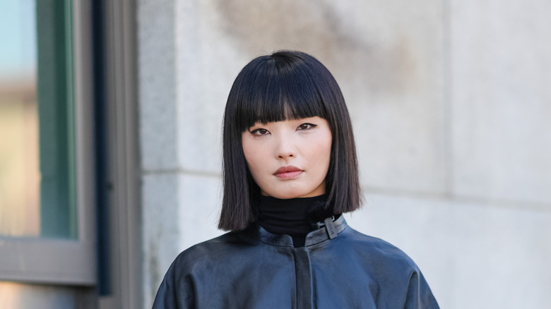 A woman with blunt bangs and a bob hairstyle looking at the camera