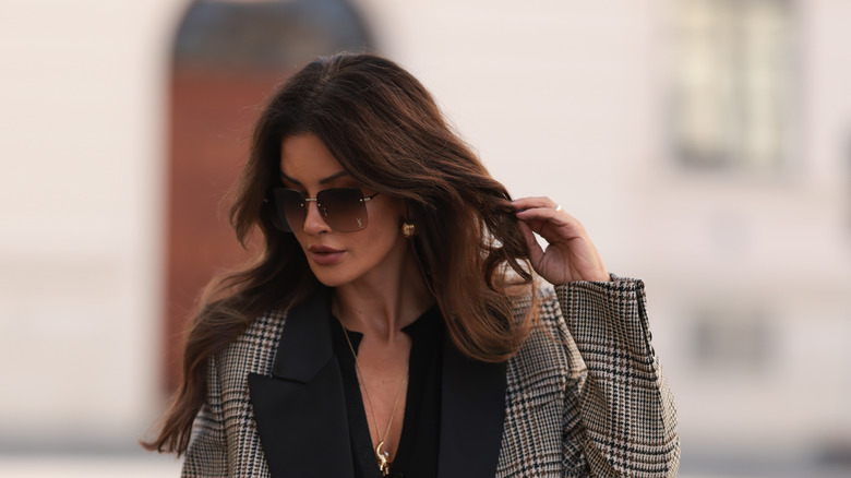 A woman with long wavy hair wearing sunglasses