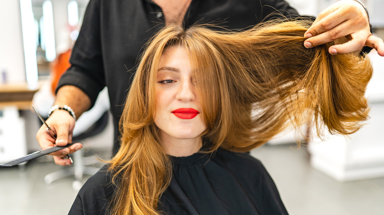 A woman with long red hair getting a haircut