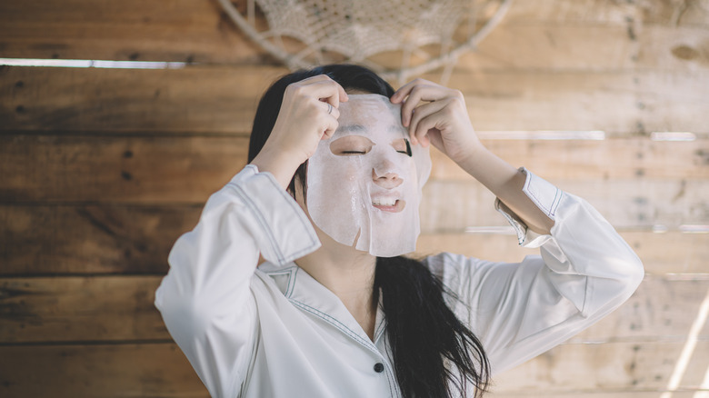 Woman applies sheet mask