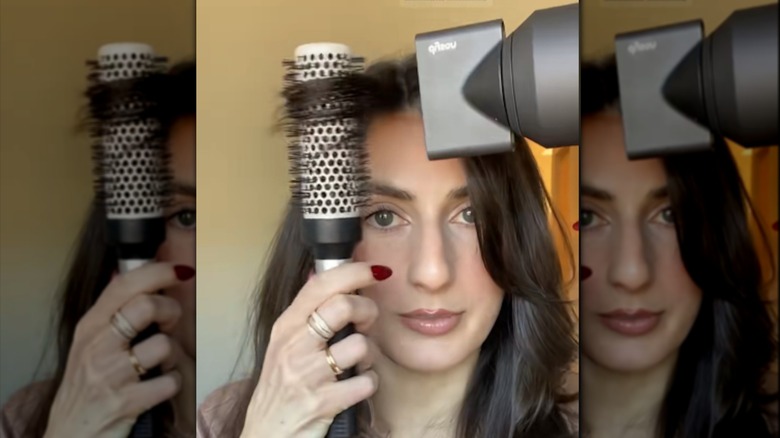 A woman blow drying her bangs with a round brush