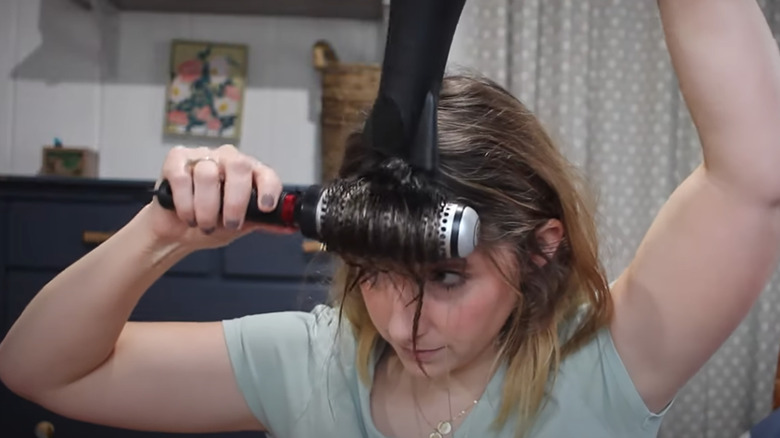 Woman blow drying curtain bangs