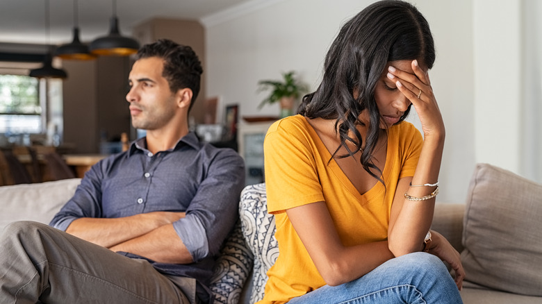 young couple in unhappy relationship sitting on couch