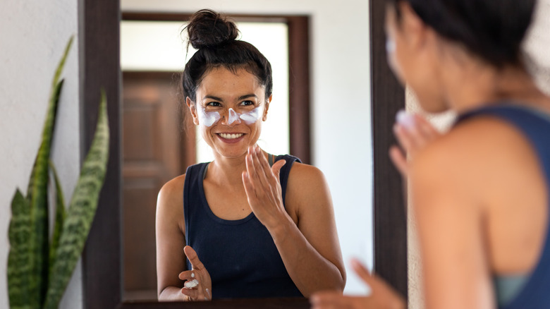 Woman applying sunscreen in mirror