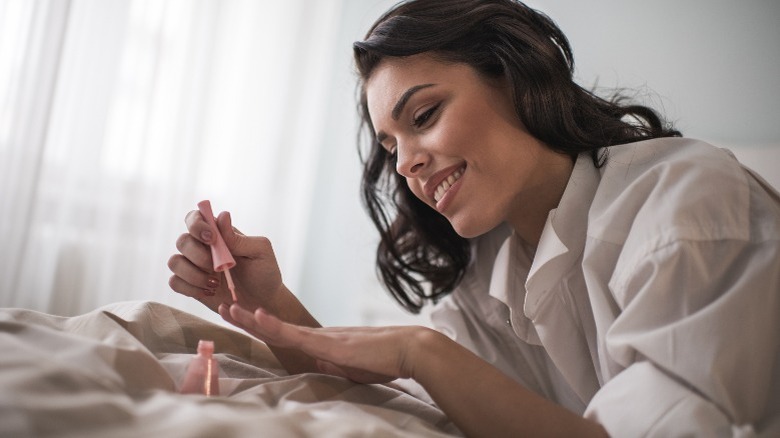 Woman painting nails with pink polish 