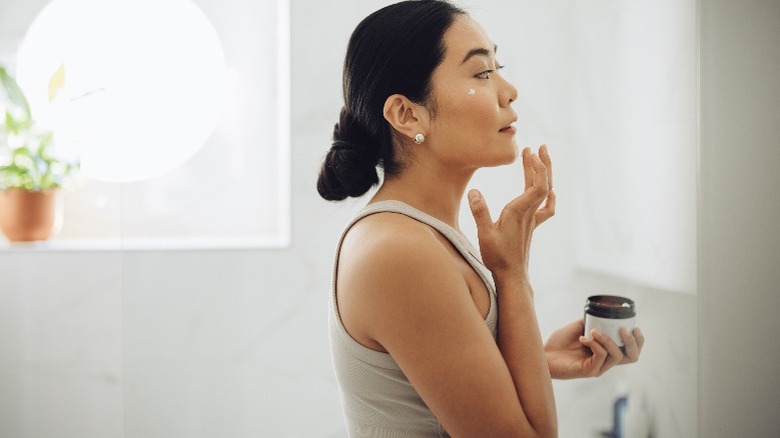 Woman applying cosmetic product to face using fingers