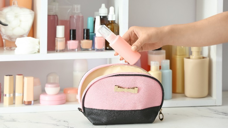 Person placing cosmetic item in bag