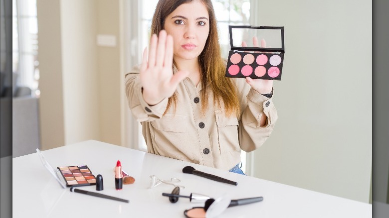 Woman holding hand up with makeup powder palette