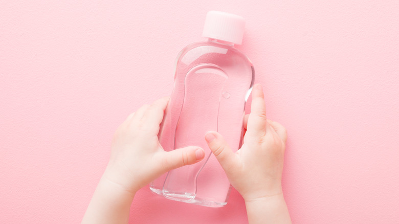 Baby hands holding skincare bottle