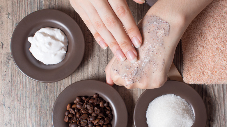 Woman applying exfoliating scrub on hand