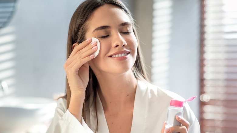 Woman cleansing with micellar water on cotton pad