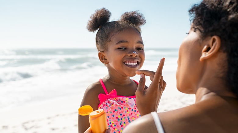 little girl wearing sunscreen on beach
