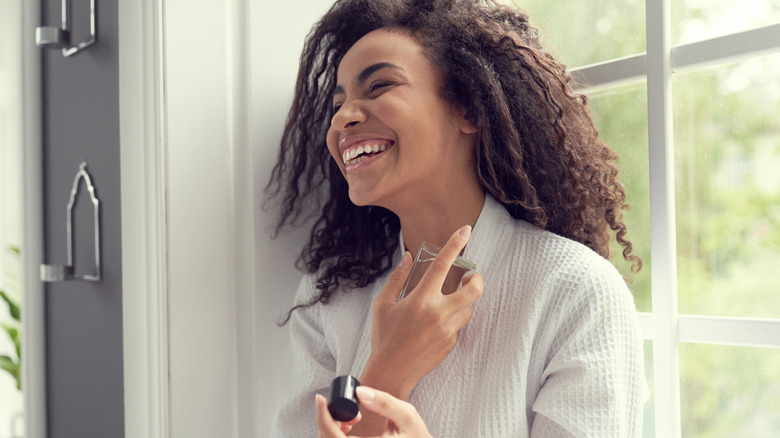 smiling woman applying perfume