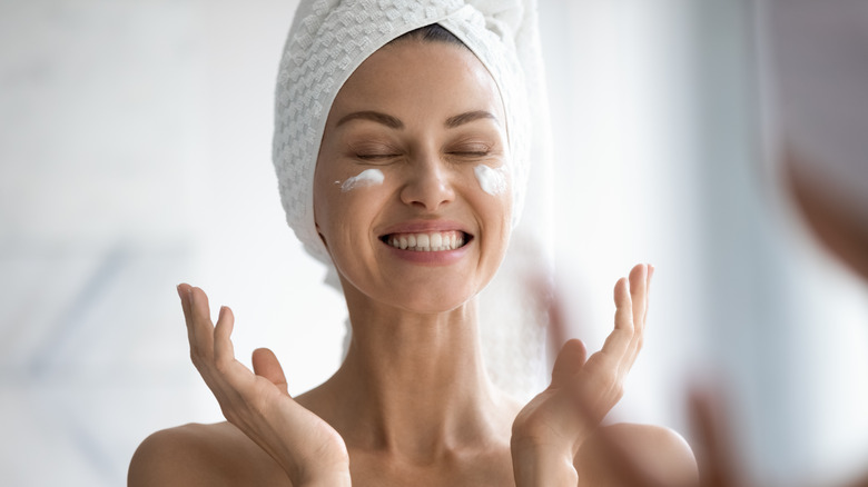 Woman doing skincare in the bathroom applying cream