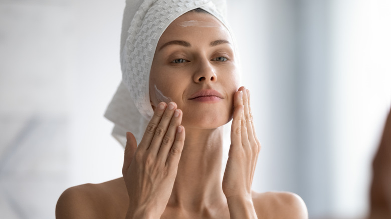 Woman doing skincare in the bathroom applying cream