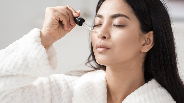 Woman doing skincare in the bathroom applying oil