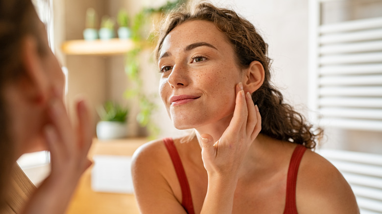 Woman looking at her skin in the mirror