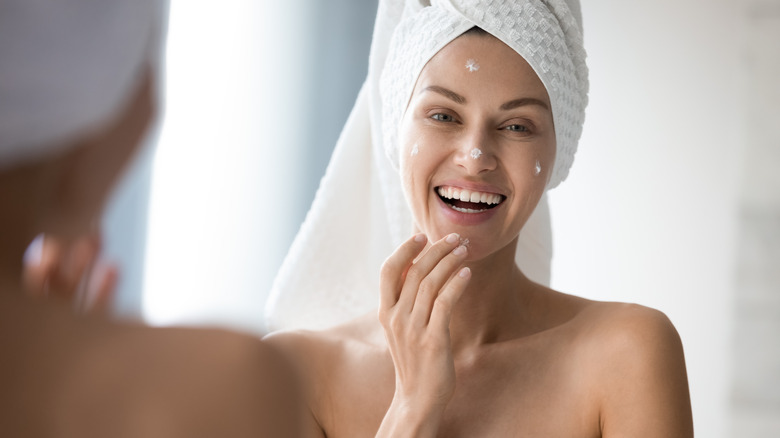 Woman doing skincare in the bathroom applying cream