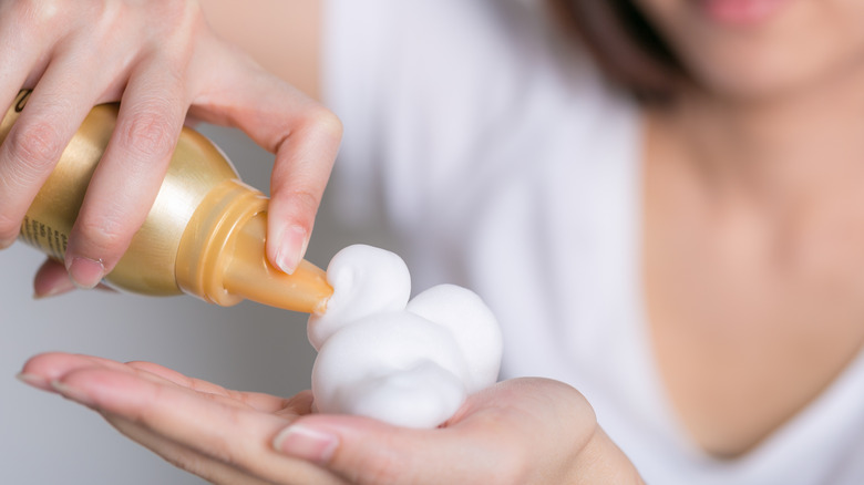 woman squeezing hair mousse into hand