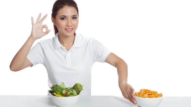 woman picking salad over chips