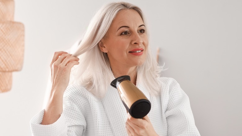 Blonde woman blow-drying hair 