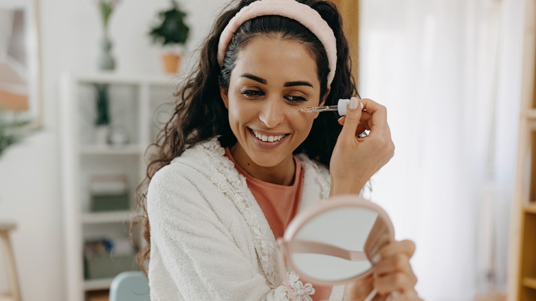 smiling woman applying face serum