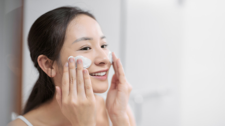 Woman applying facial cleanser
