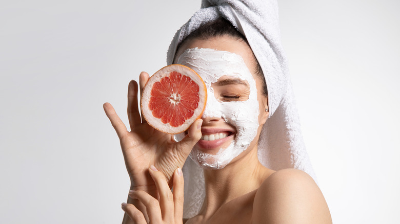 smiling young woman in a face mask holding a grapefruit