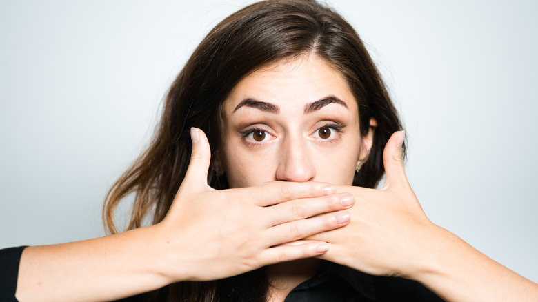 woman hiding mouth with hands