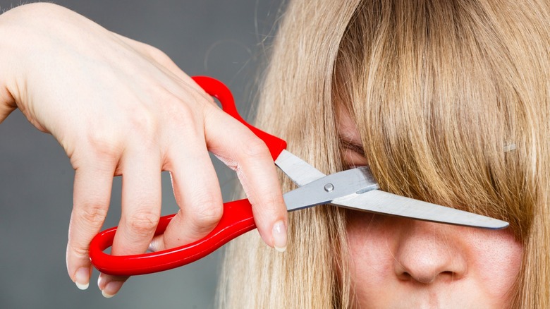 Blonde woman cutting her bangs