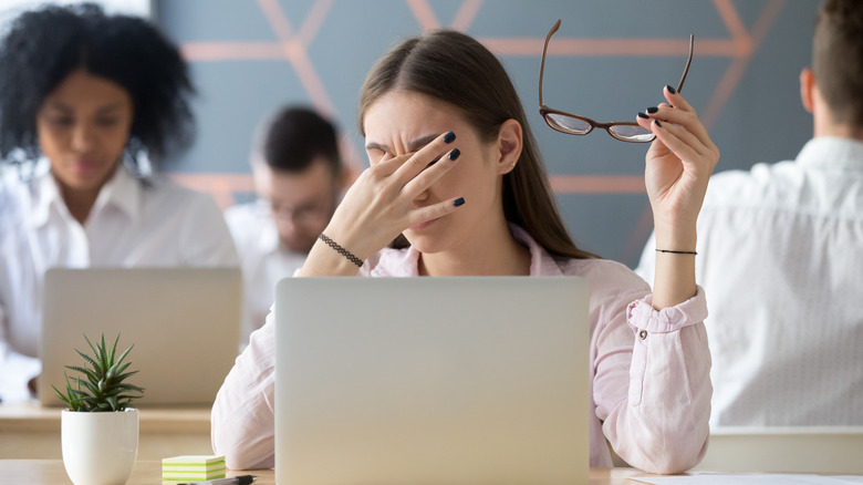 woman stressed taking off glasses looking at computer