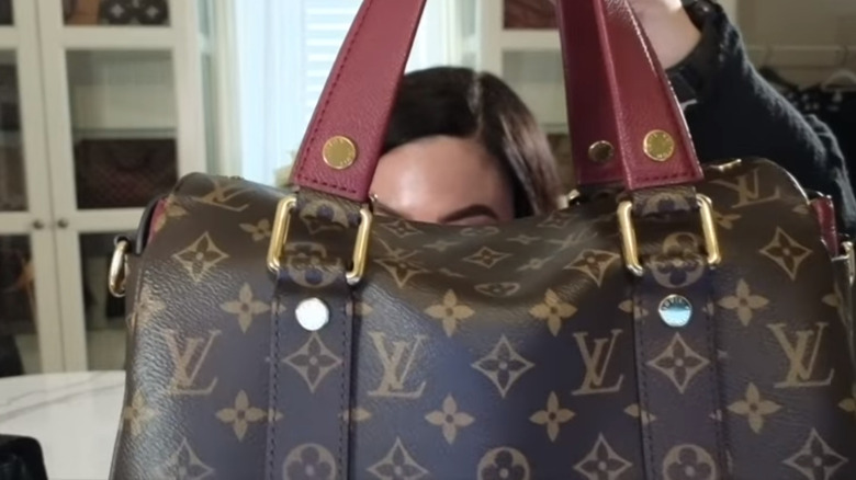 Claudia holds a Louis Vuitton bag