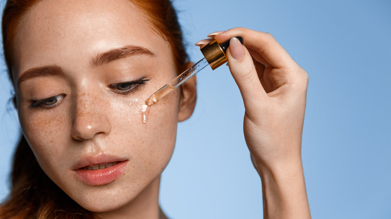 Woman applying serum to face