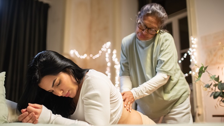 Midwife offering back support to woman