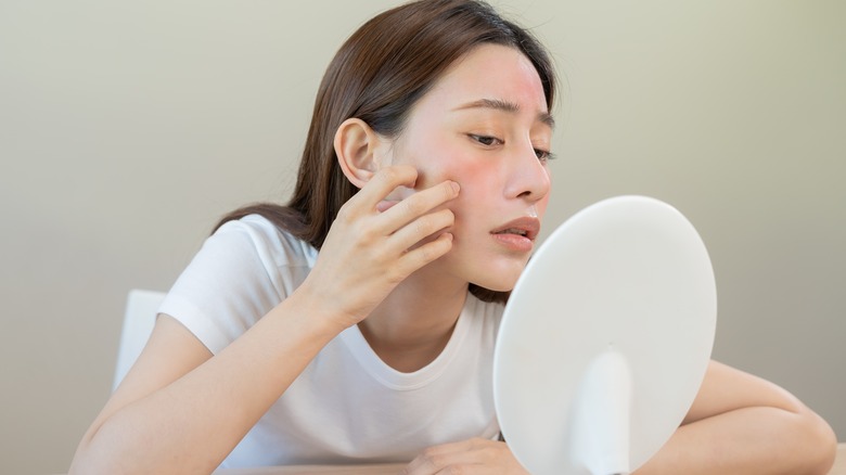 women touching dry skin in mirror