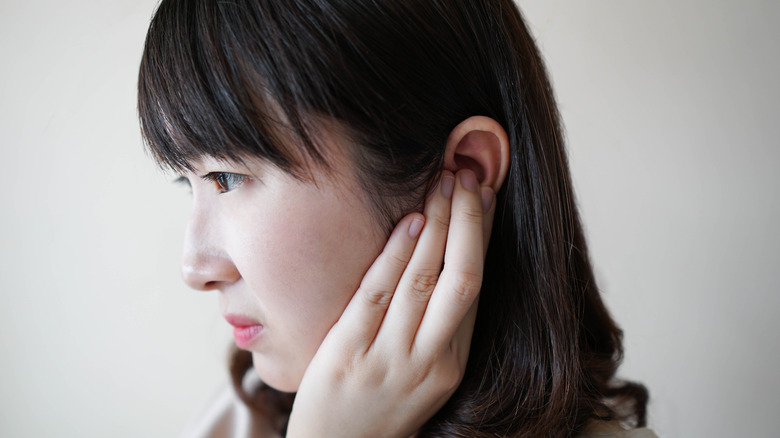 young asian woman holding ear in pain