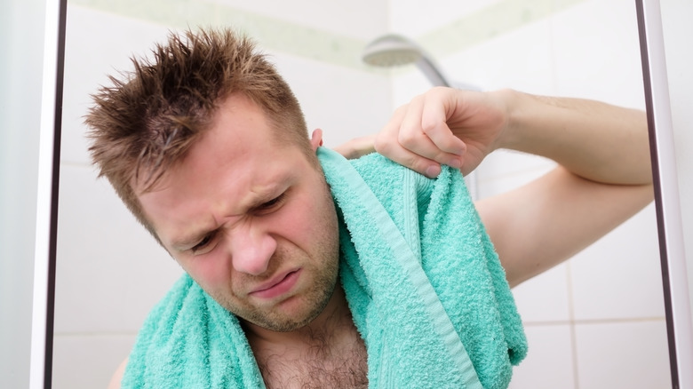 young man cleaning his ear towel shower