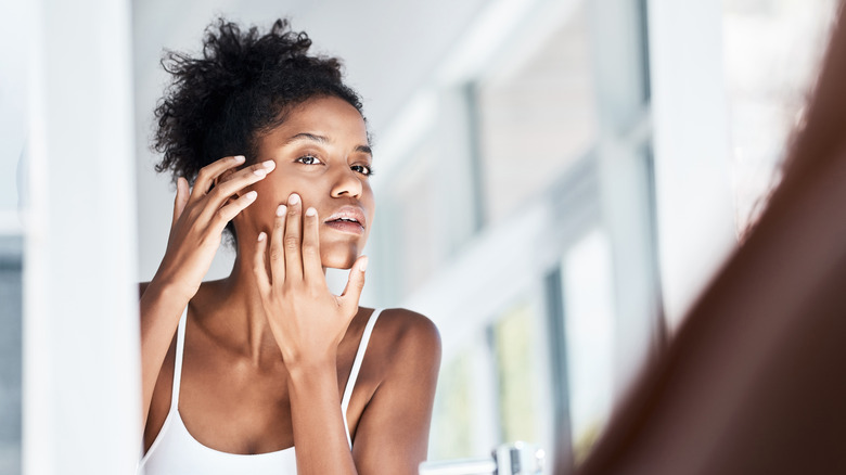 Woman looking at pimples in a mirror 