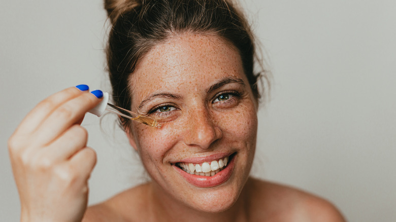 Smiling woman holding a dropper to her face 