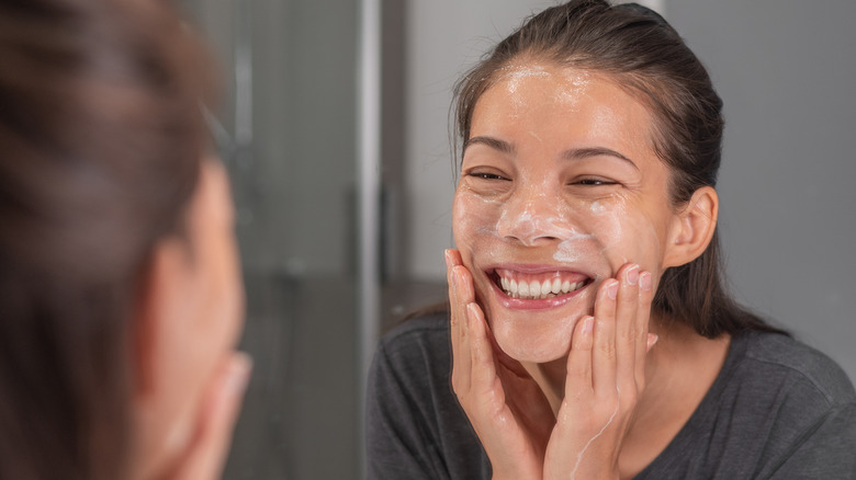 Female in mirror scrubbing face