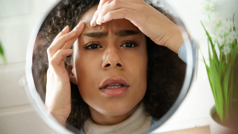 woman checking zit in mirror